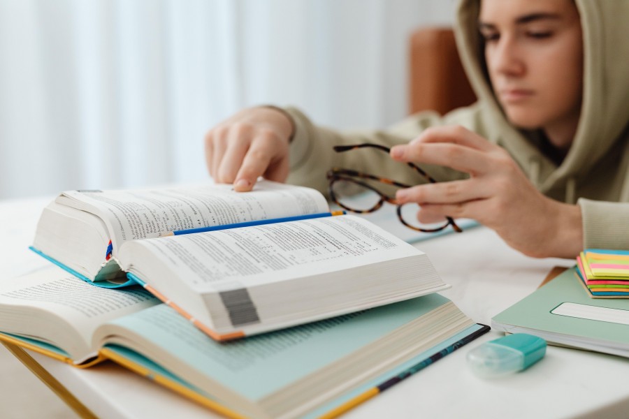 A male student sitting at a desk trying to study but showing an obvious lack of motivation.